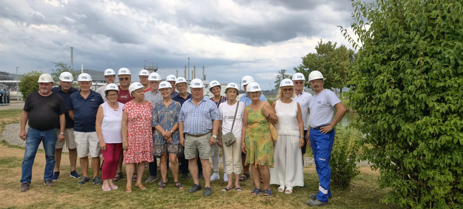 Die Teilnehmerinnen und Teilnehmer der Werksbesichtigung mit Schutzhelmen vor der Speicheranlage der RAG Austria in Haidach